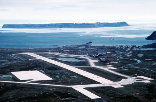 Thule AFB with its airport, pier, and ice-covered ocean in the summer. The island is Saunders Island. The ship is most likely the CCGS Henry Larsen in 2007. [Credit: Unknown]